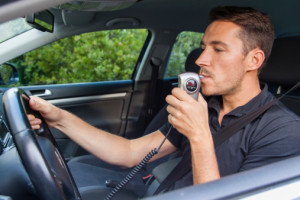 Man in car blowing into ignition breathalyzer