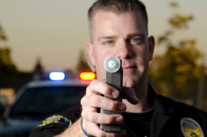 A police officer holds the breath test machine for a suspect